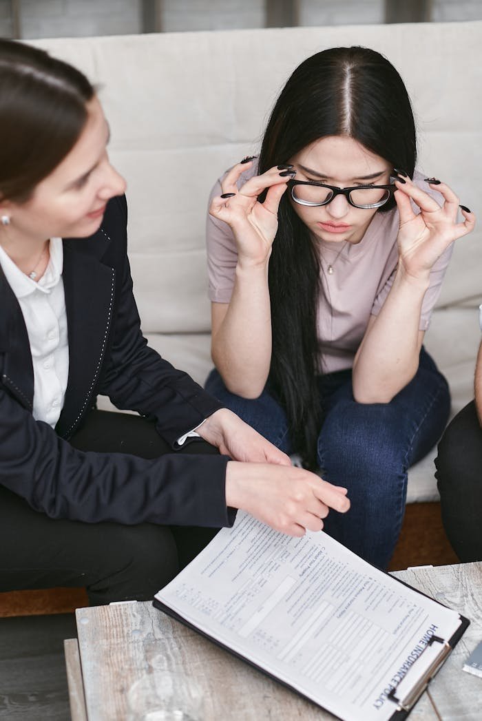 Focused businesswomen discuss contract details while reviewing important documents in an office setting.
