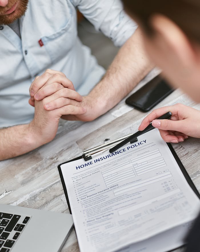 Two adults reviewing a home insurance policy document on a table with electronic devices.
