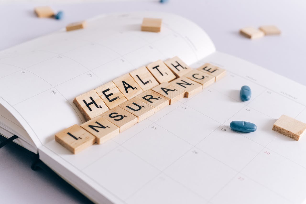 about-04 Scrabble tiles spelling Health Insurance on a calendar with pills.